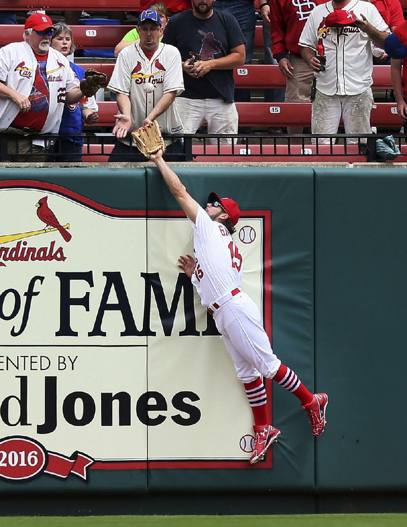 St. Louis center fielder Randal Grichuk reaches over the wall to take a home run away from Chicago’s Anthony Rizzo in the first inning of the Cardinals’ 5-3 rain-delayed victory Wednesday.