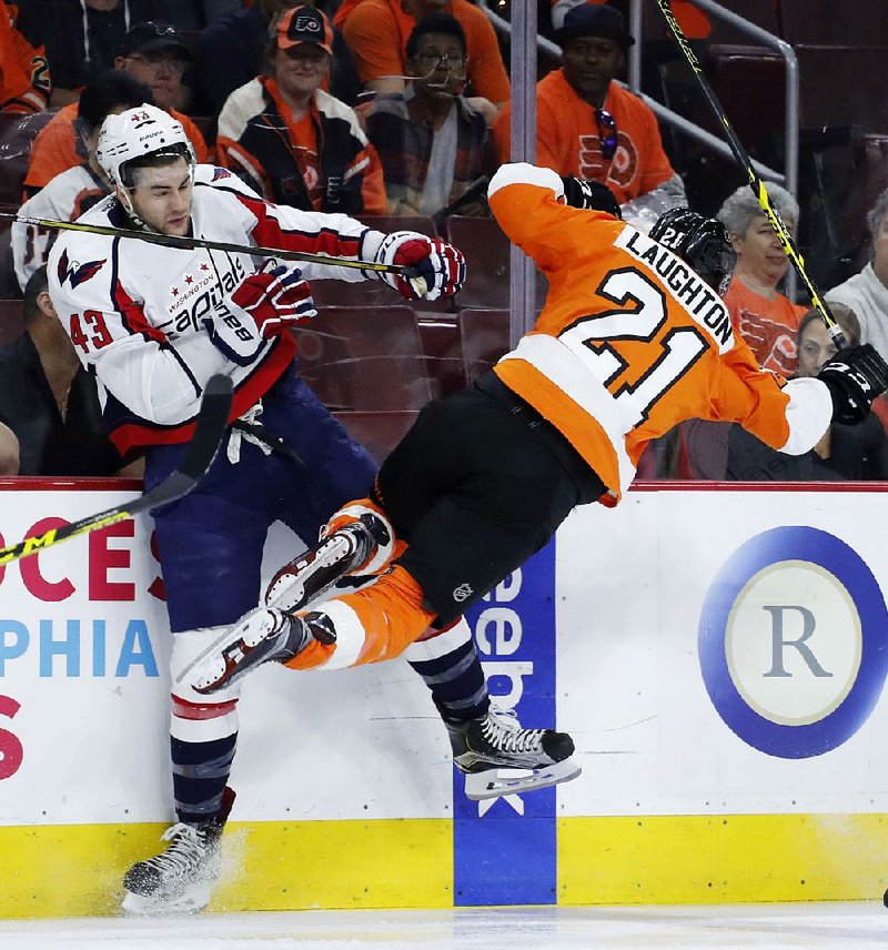 Philadelphia’s Scott Laughton (21) collides with Washington’s Tom Wilson during the first period of the Flyers’ 2-1 victory over the Capitals on Wednesday in Philadelphia. The Capitals, who were the top seed in the Eastern Conference and won the Presidents’ Trophy for the most victories during the regular season, still lead the series 3-1. 