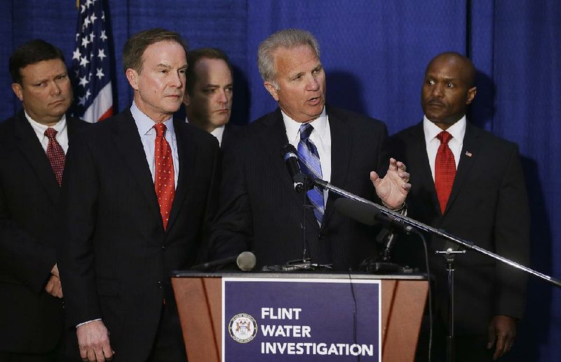 Michigan Attorney General Bill Schuette (second from left) and David Leyton (at microphone), Genesee County, Mich., prosecuting attorney, discuss the criminal charges in the Flint water crisis. Schuette said more charges are planned, adding, “No one is off the table.” 