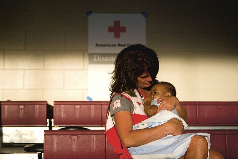 A Red Cross volunteer comforts a child after a natural disaster. The American Red Cross serving Northwest Arkansas will hold the Celebration of Heroes on May 5 at the John Q. Hammons Center in Rogers.