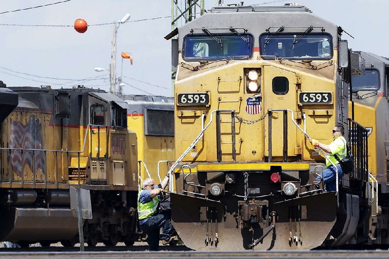A train engineer (left) climbs down from a Union Pacific locomotive while another climbs on at a rail yard in Council Bluffs, Iowa, in this file photo. The railroad said Thursday that its profit fell 15 percent on a drop in the amount of freight hauled.