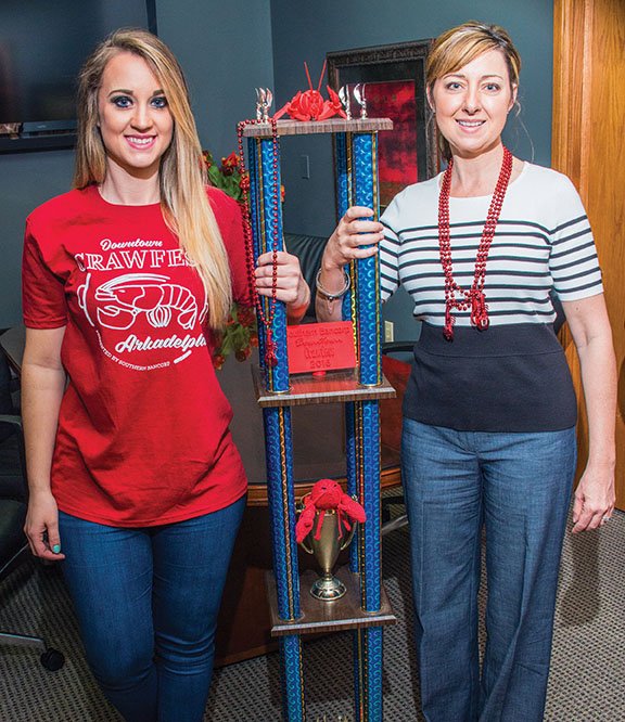 Afton Oelmann, left, winner of the 2015 crawfish-eating contest, and Shelley Loe, executive vice president of the Arkadelphia Chamber of Commerce, display the new trophy that will be awarded to this year’s winner. The crawfish-eating contest is part of Downtown Crawfest, which will take place Friday and Saturday in Arkadelphia.