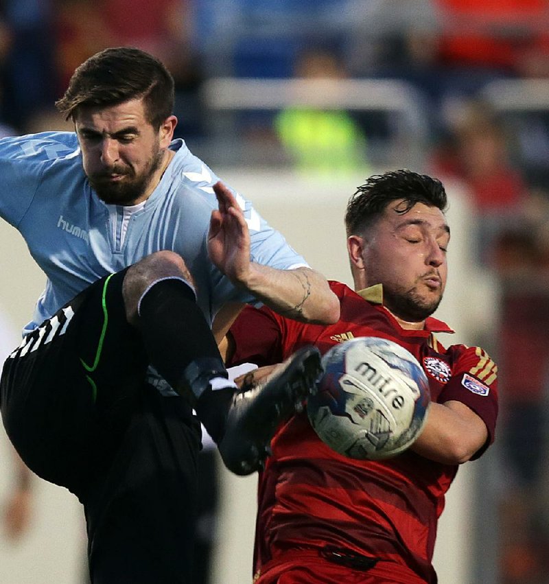 The Little Rock Rangers’ Josh Reed (right) gets tangled up with Memphis City FC’s Neil Cummings during the Rangers’ 2-1 victory in their inaugural game Friday at War Memorial Stadium.