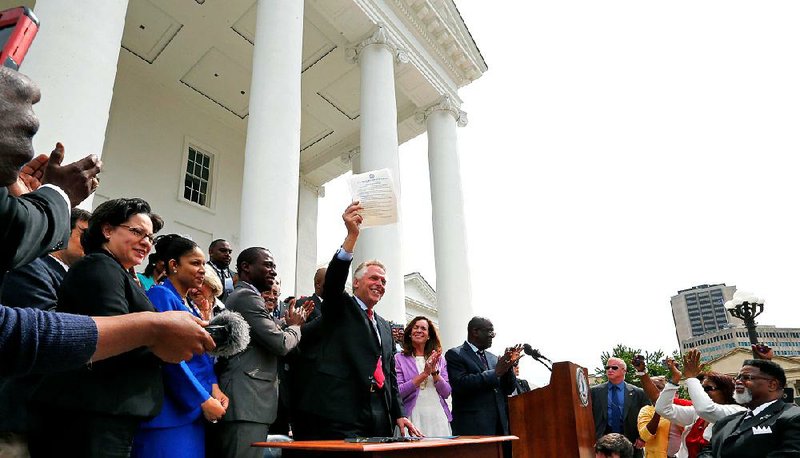 Gov. Terry McAuliffe holds up the order he signed to restore rights to felons in Virginia at the Capitol in Richmond on Friday.