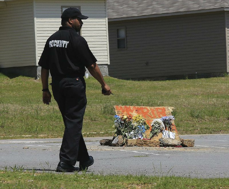 A security officer walks near a makeshift memorial Friday afternoon in the parking lot of Sylvan Hills High School. A 17-year-old student, Bryan Allen Thompson, was killed Thursday off-campus, police said. 