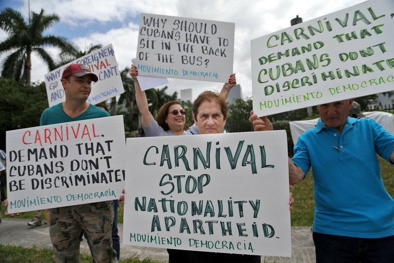 In this April 12, 2016 file photo, Victor Garcia, of Miami, from left, Maria Hernandez and Miriam Dominguez, protest against Carnival Corporation as they hold a rally in Doral, Fla. 