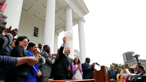 Gov. Terry McAuliffe holds up the order he signed to restore rights to felons in Virginia at the Capitol in Richmond, Va., on Friday, April 22, 2016. 