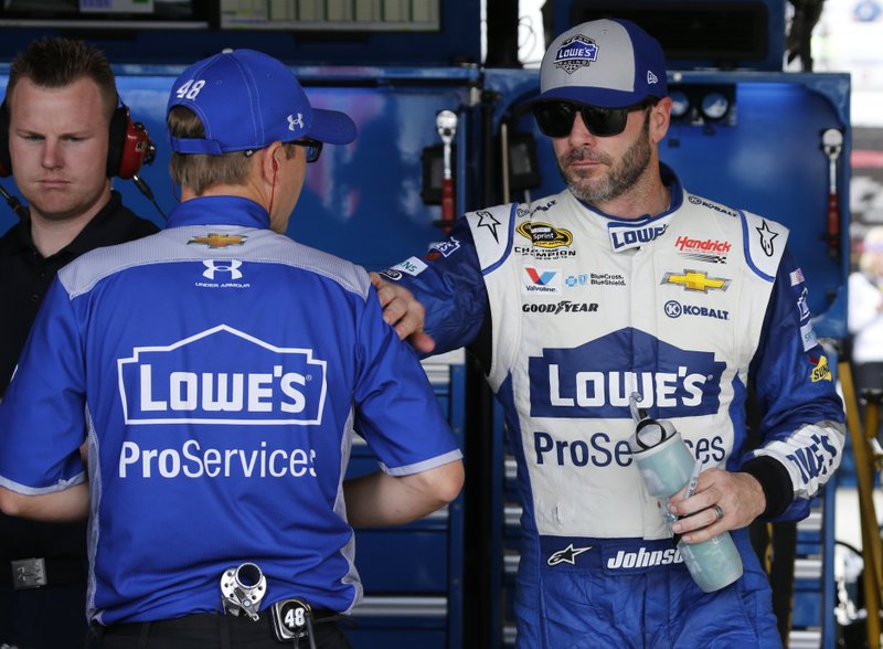 Jimmie Johnson, right, greets a crew member in the garage after practice for Sunday's NASCAR Sprint Cup auto race at Richmond International Raceway in Richmond, Va., Saturday, April 23, 2016. 