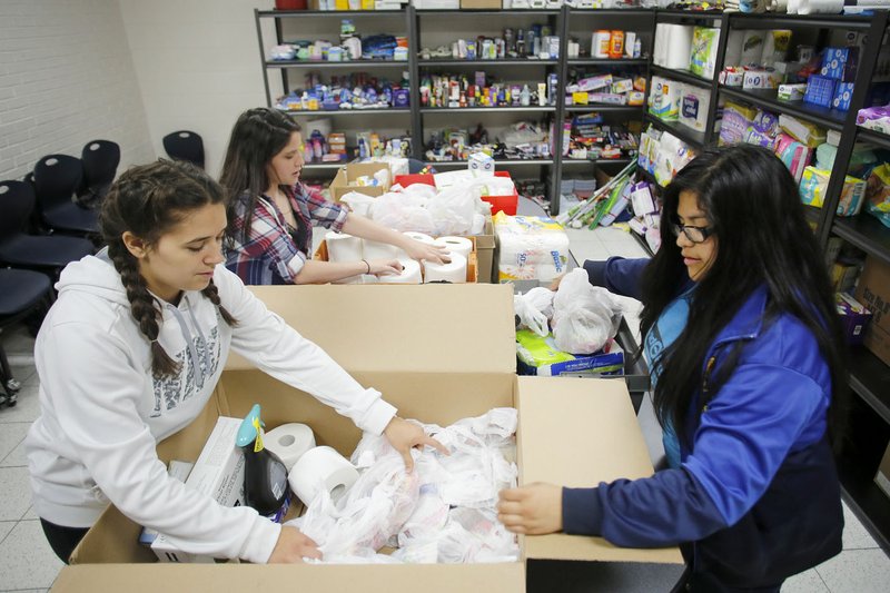 Jasmine Jones (from left), Shelby Bartram and Luz Carpio, all eighth-graders in the Environmental and Spatial Technologies Initiative at Central Junior High School, collect household items Wednesday for a family in the Central Junior High School Thrift Store at the school in Springdale. The household items are distributed to families in need with students at the school. This is the first semester for operation of the store that was created through the Student Directed Learning program a the school.