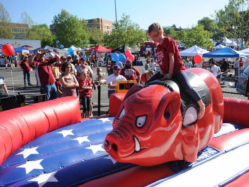 Lacey Johnson, 8, of Clarksville laughs Saturday as she tries to hang on while riding a mechanical Razorback during RazorFest in Fayetteville. The family-friendly event takes place each year ahead of the University of Arkansas’ spring football game. 