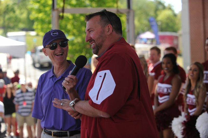 NWA Democrat-Gazette/ANDY SHUPE University of Arkansas football coach Bret Bielema (center) laughs Saturday as he speaks to the crowd alongside Rick Schaeffer during Razorfest ahead of the University of Arkansas spring football game at Razorback Stadium in Fayetteville. The event drew 40,000 people in 2015 and about 8,700 pounds of food was collected.