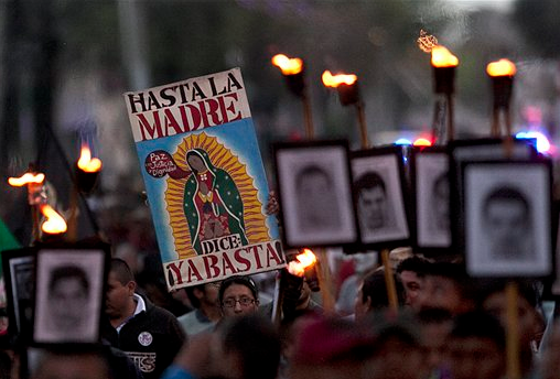 In this Dec. 26, 2015, file photo, relatives of the 43 missing students from the Isidro Burgos rural teachers' college hold pictures of their missing loved ones during a protest in Mexico City. 