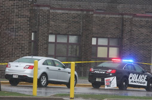 Two Antigo Police Department vehicles sit in front of the entrance to Antigo High School, where an 18-year-old gunman opened fire late Saturday outside of a prom at the school.