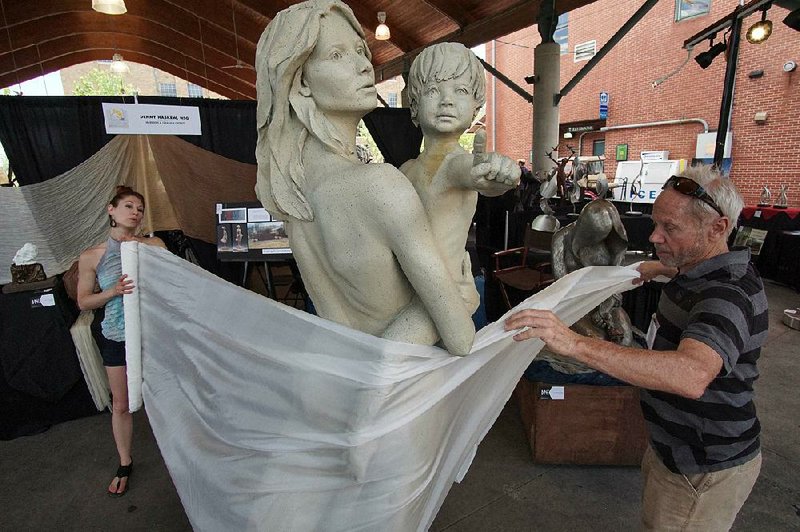 Abbie Powers (left), an installation and performance artist, and sculptor Denny Haskew, both of Loveland, Colo., experiment with wrapping silk around a piece Sunday during the Sculpture at the River Market Show and Sale in Little Rock.