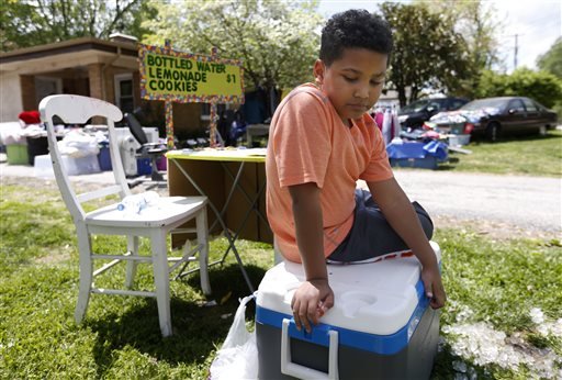 In this April 22, 2016, photo, Tristan Jacobson sits on a water cooler in front of his lemonade stand outside his home in Springfield, Mo. 