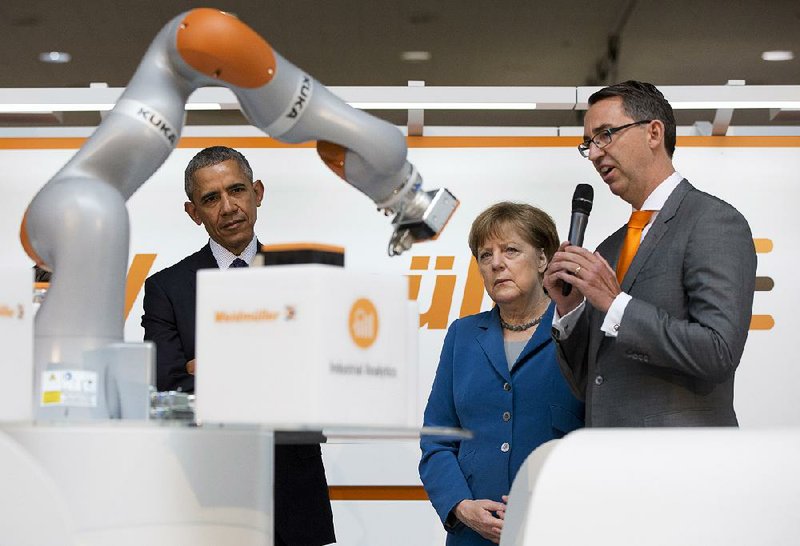 President Barack Obama and German Chancellor Angela Merkel watch a demonstration at the Weidmuller booth Monday during a tour of the Hanover Messe, the world’s largest industrial technology trade fair, in Hanover in northern Germany.
