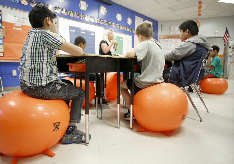 Brooke Buckley (center) reads Shiloh by Phyllis Reynolds Naylor on Monday to students in her fourth-grade class at Asbell Elementary School in Fayetteville. Buckley received a $3,800 grant in the fall from money given by Clyde and Robbie Selle and Martha Albright McCandless. She used the money to transform her classroom into the Fit Lit Lab.