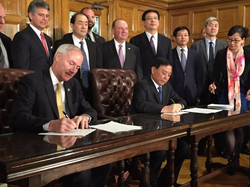 Gov. Asa Hutchinson, left, and Hongxin Li, chairman and founder of Sun Paper, sign a memorandum of understanding after the announcement that the firm will create a $1 billion mill in Arkansas. 
