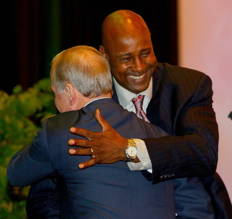 Former Little Rock Hall and Arkansas Razorbacks standout Sidney Moncrief (right) is embraced by Mack McLarty at the Legacy Awards luncheon Tuesday in Little Rock.