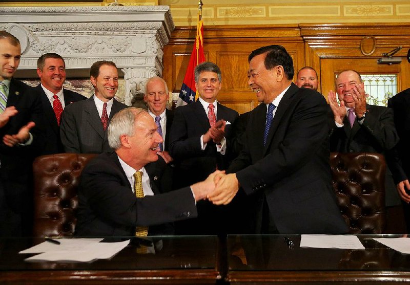 Gov. Asa Hutchinson and Hongxin Li, chairman and founder of Sun Paper Industry Joint Stock Co., seal the agreement Tuesday that Hutchinson called “a real boost” for south Arkansas’ timber industry. 