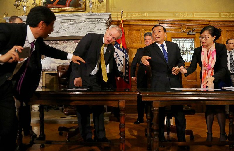 FILE — Aides get Gov. Asa Hutchinson and Sun Paper executive Hongxin Li to their places on April 26, 2016, at the state Capitol in preparation for a signing ceremony for Sun Paper’s pulp mill in Clark County.