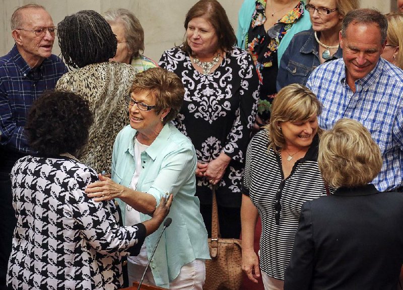 Linda Taylor (center left), widow of former state Sen. Jerry Taylor, and her daughter, Pam DePriest (center right), are greeted Tuesday on the floor of the Senate after passage of a Senate memorial resolution honoring Taylor and his contributions to the state in 30 years of service in the Legislature, as Pine Bluff mayor and as a city councilman. 