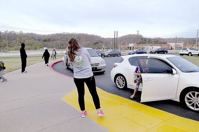 Lynn Atkins/The Weekly Vista Teachers help students out of the cars as they arrive at school between 7 and 7:30. A speaker plays a different genre of music every day to keep the mood positive.