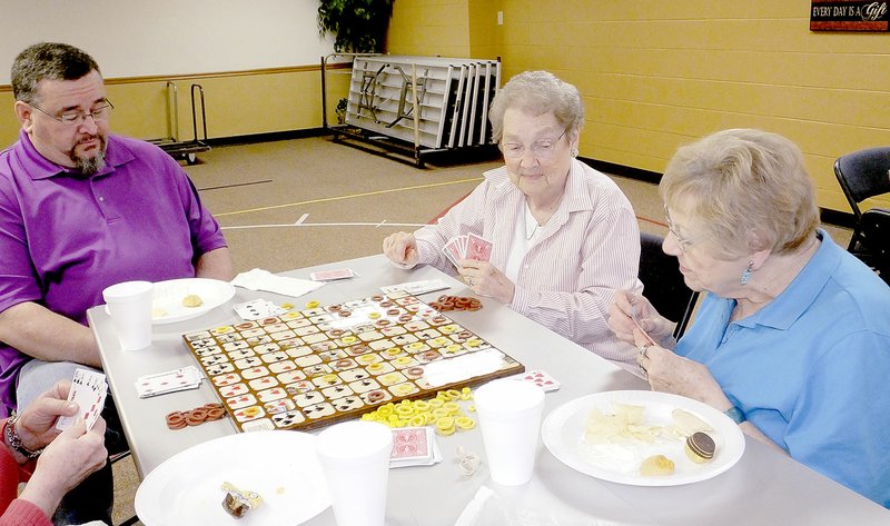 Lynn Atkins/The Weekly Vista Associate Pastor Robert McGee, left, plays Sequence with Kitty Wagner and Marjorie Shafer at the Bella Vista Baptist Church on Thursday. On the second Thursday of each month, a Fun Day is held and members as well as guests are encouraged to bring games and snacks to share and enjoy.