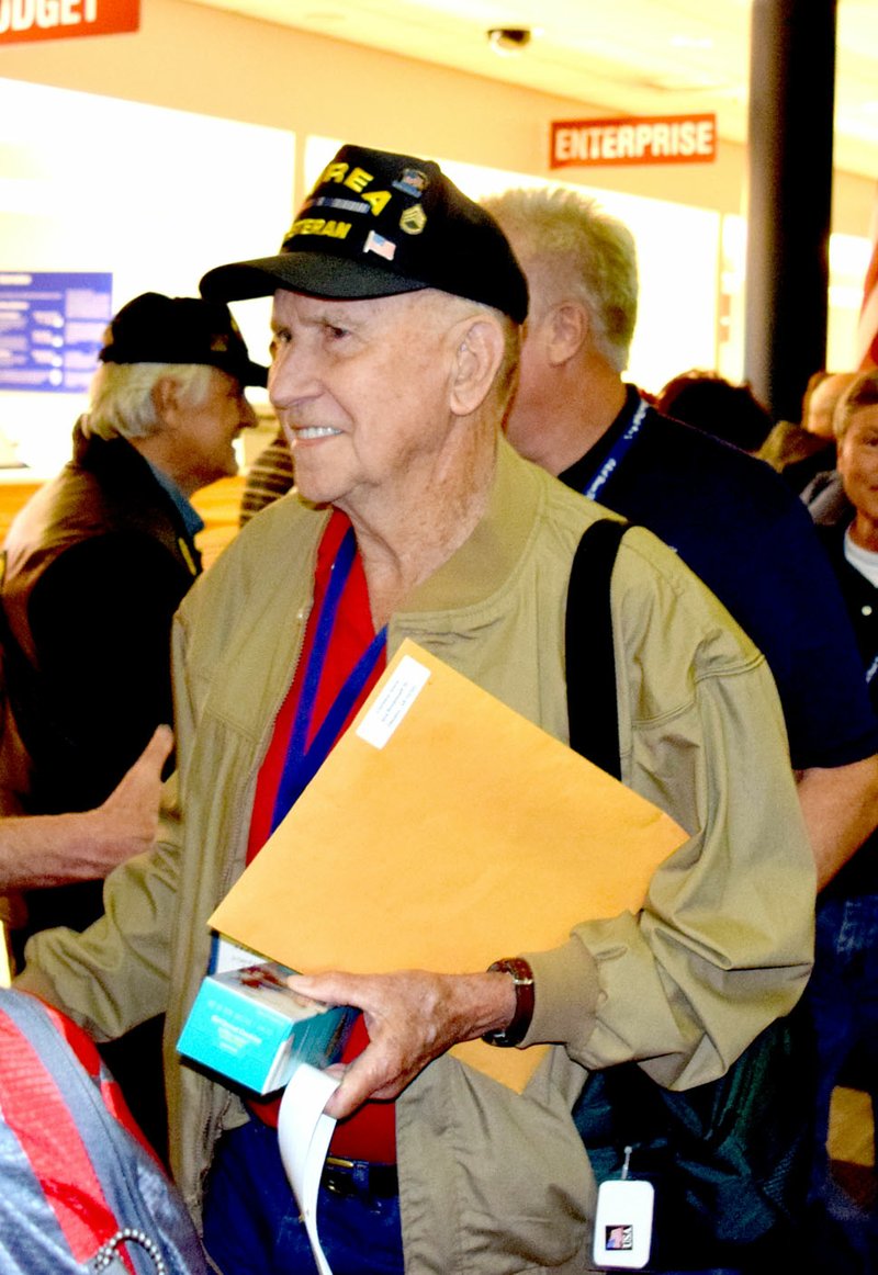 Photo by Mike Eckels Clarence Amos, from Decatur, is greeted by well wishers as he walks toward a waiting bus after a day in the nation&#8217;s capitol April 20. Amos was one of 14 area military veterans who participated in the 2016 Honor Flight from Northwest Arkansas Regional Airport to Washington, D.C.