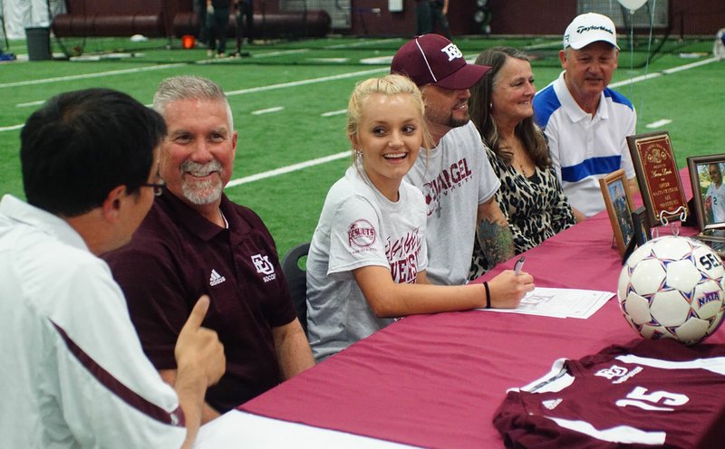 Photo by Randy Moll Fabrizio Campagnola, Gentry girls soccer coach, gives Ana Linch, a Gentry senior, a thumb&#8217;s up as she signed a letter of intent Friday in the Pioneer Activities Complex to attend Evangel University in Springfield, Mo., to play soccer. Her father, Bill Linch Jr., her grandmother, Trish Linch, and her grandfather, Bill Linch Sr., looked on. Bruce Deaton (second from left) is the women&#8217;s soccer coach at Evangel.
