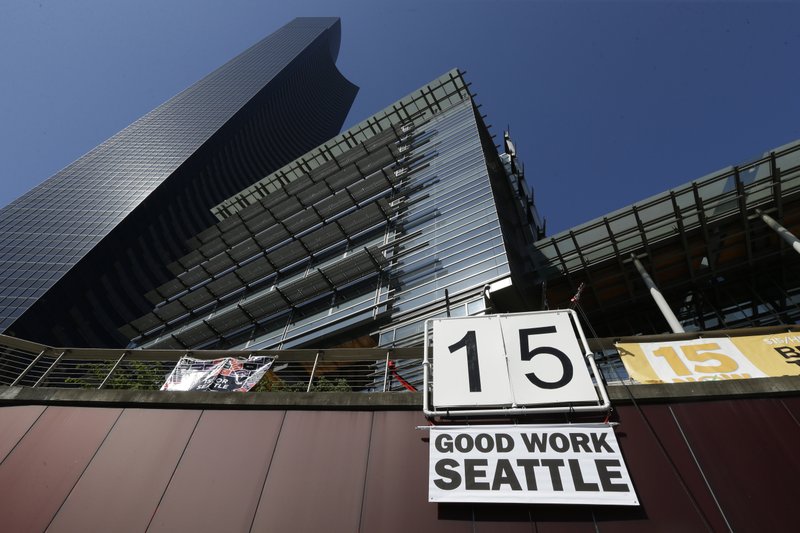  In this June 2, 2014, file photo, a sign that reads "15 Good Work Seattle" is displayed below Seattle City Hall, right, and the Columbia Center building, left, after the Seattle City Council passed a $15 minimum wage measure. 