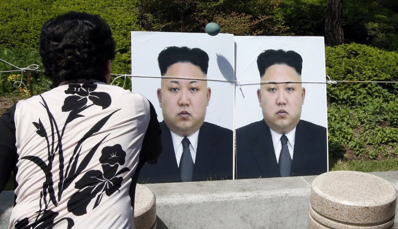 A North Korean defector throws a balloon containing a colored liquid against portraits of North Korean leader Kim Jong Un during a rally against North Korea in Seoul, South Korea, Tuesday, April 26, 2016. 