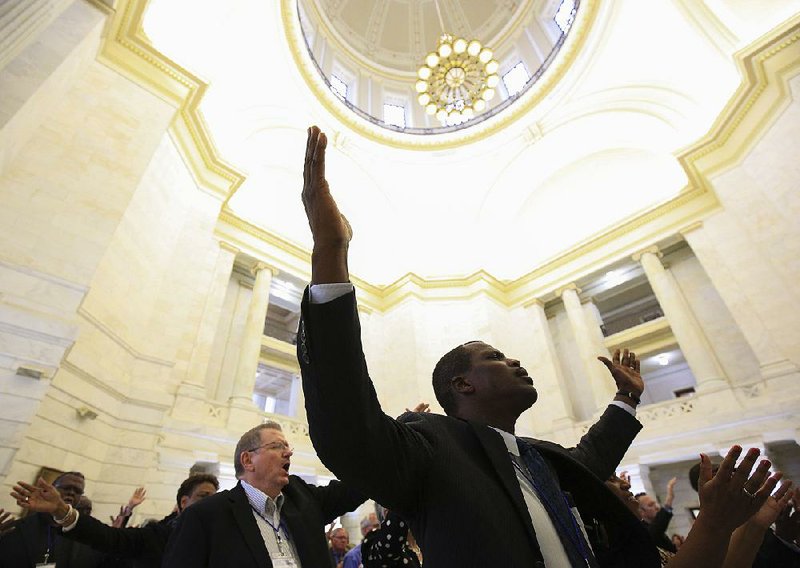 Pastor Iverson Jackson of Zoe Bible Church in Little Rock joins in a prayer Wednesday morning during Pastor Day at the Capitol. The event included speeches from the governor and legislators as well as breakout sessions for attendees. 