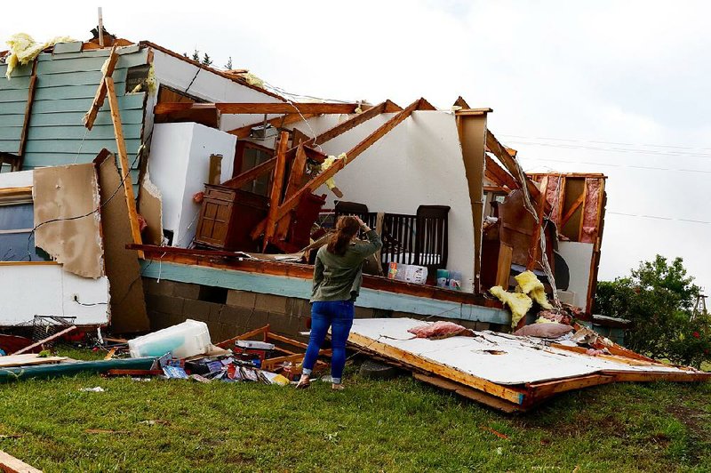 Averie Young stands outside her grandparents’ house Wednesday in Sherman, Texas, after high winds tore the roof off while they were sleeping and caused other major damage. Strong storms Tuesday and Wednesday caused damage in parts of the Midwest and the South. One woman was killed in Tomball, Texas, when a tree fell on her house. 