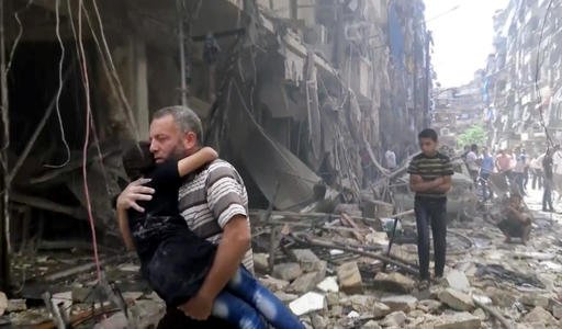 In this image made from video and posted online from Validated UGC, a man carries a child after airstrikes hit Aleppo, Syria, on Thursday, April 28, 2016.