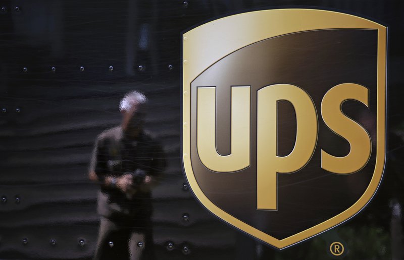 In this June 20, 2014, file photo, the United Parcel Service logo is seen on the side of a truck as driver Marty Thompson is reflected returning from a delivery in Cumming, Ga.  