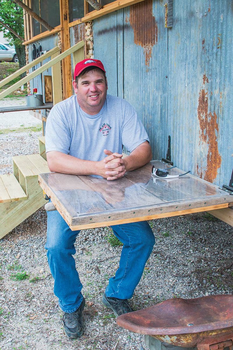 Scott Stewart sits at the flip-down table of the Glamper, or glamorous camper, a Slabtown Customs-created tiny house that has a rustic theme but pops with pizzazz.