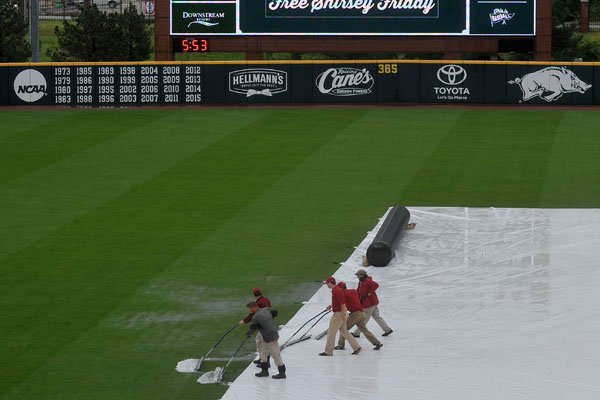 Grounds crews push the water off the infield tarp Friday, April 29, 2016, before the start of Fridays game at Baum Stadium in Fayetteville. 