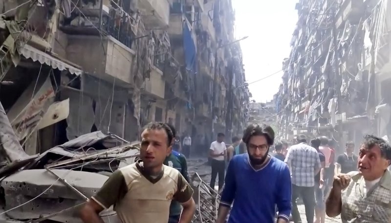 In this image made from video and posted online from Validated UGC, men look at damaged buildings after airstrikes hit Aleppo, Syria, Thursday, April 28, 2016. A Syrian monitoring group and a first-responders team say new airstrikes on the rebel-held part of the contested city of Aleppo have killed over a dozen people and brought down at least one residential building. The new violence on Thursday brings the death toll in the past 24-hours in the deeply divided city to at least 61 killed. (Validated UGC via AP video)

