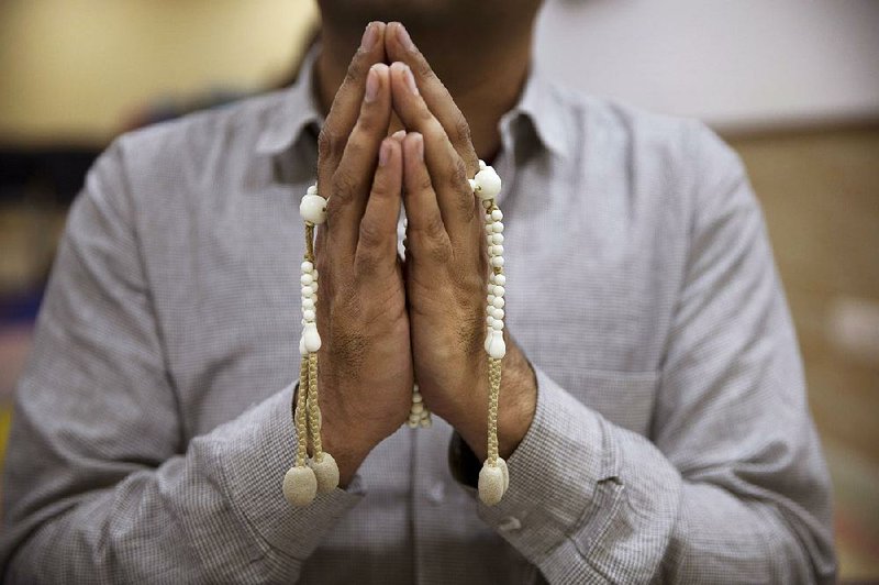 An Indian man holds prayer beads as he chants Buddhist prayers. Some Hindus in India have embraced the practice and gather daily or monthly with others to chant mantras.