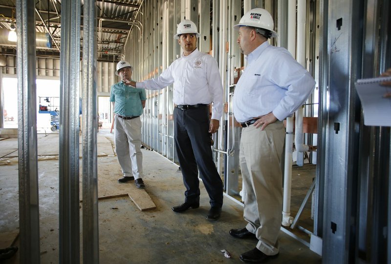 Joe Rollins (center), principal at Don Tyson School of Innovation, gives a tour April 21 of the new campus with John Nappier (right) with Freight Farms and Jerry Martin with Vet Veggie in Springdale.