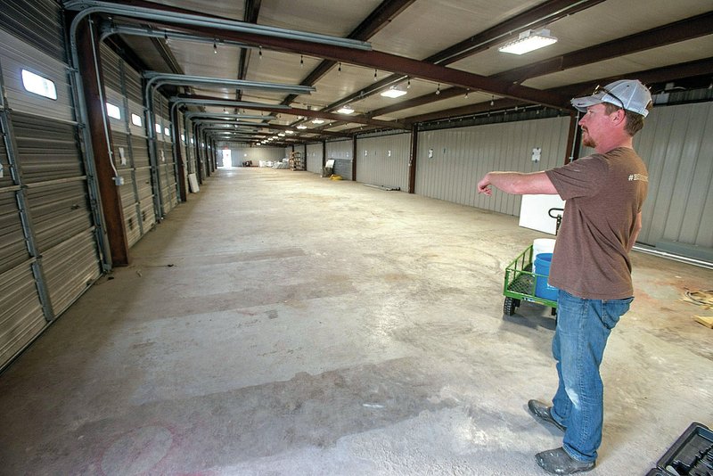 Ryan Neal, farmers market manager for Main Street Rogers, shows some of the facilities Tuesday for the new downtown Farmers Market in Rogers. The space features several indoor spaces for vendors, bay doors for easy loading of product and a courtyard with a grass pave system that will allow vehicle traffic on grass.