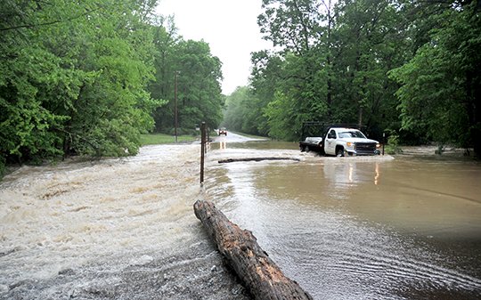 The Sentinel-Record/Mara Kuhn WATERY CROSSING: A truck drives across the second low-water bridge from Blakely Dam Road on Owl Creek Road after heavy rains on Friday caused the creek to rise over the road.