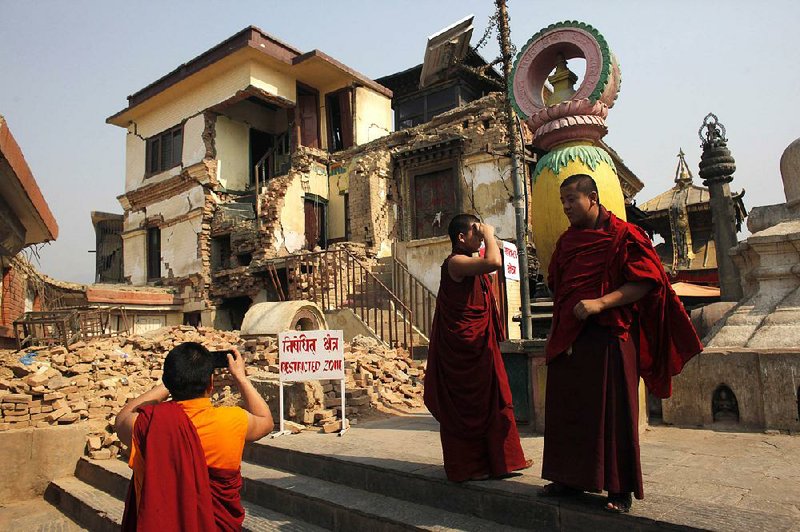 A monk in Kathmandu, Nepal, takes photographs last week at a monastery that was damaged by last year’s earthquake and has yet to be rebuilt. 