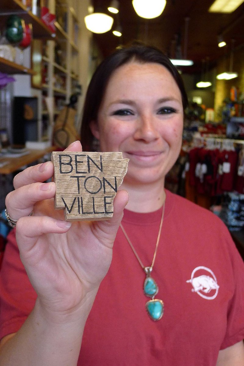 Tiffany Norwood, standing in her shop, Bleachers, shows off a magnet made from Bentonville barn wood. She expects more customers will buy such trinkets during the second Bentonville Film Festival, which begins this week. 