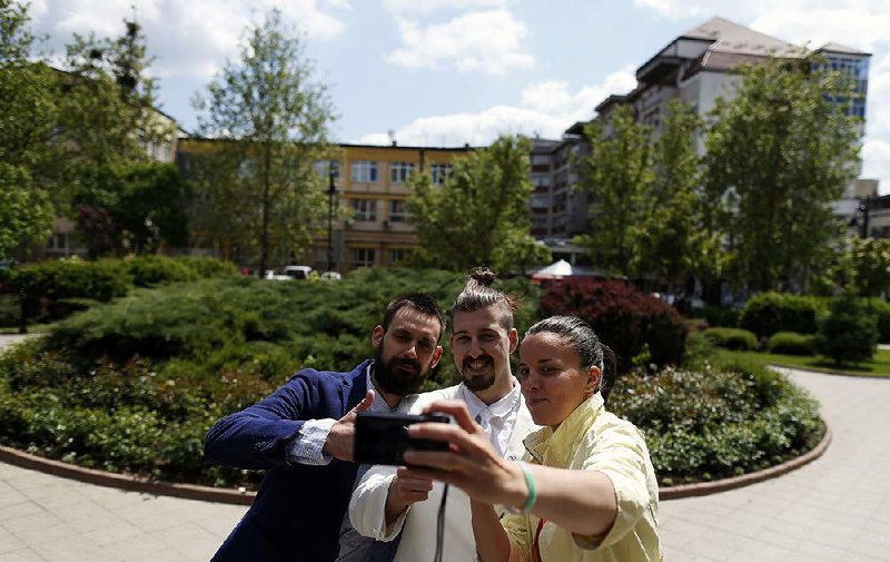 Luka Maksimovic (centre) poses as a sleazy, bejeweled politician in a white suit with his closest friend Stefan Gajic (left), known as Sticker, take a selfie Tuesday with a sympathizer in the town of Mladenovac, outside Belgrade, Serbia. Maksimovic started the campaign with his a friends as a joke but now they have been elected to local government office after placing second in the local election.