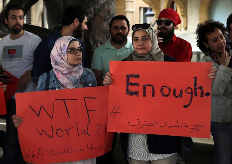 Protesters hold placards during a protest in downtown Beirut, Lebanon, Saturday, April 30, 2016, against Syrian President Bashar Assad's military operations against areas held by insurgents around the country, mostly in the northern city of Aleppo that has been the main point of violence. 