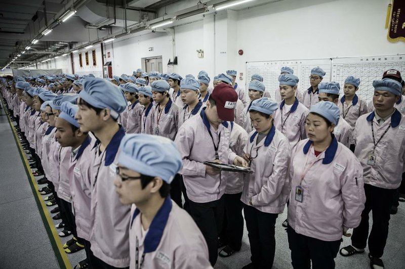 A supervisor uses an Apple iPad to check an employee’s badge during roll call at a Pegatron Corp. factory in Shanghai in mid-April.
