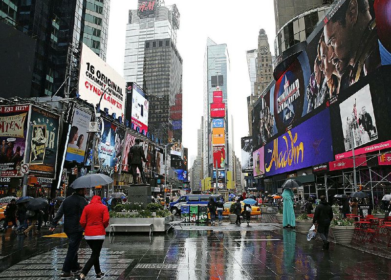 People walk through Times Square on Sunday in New York, where Clear Channel Outdoor Americas operates several billboards.