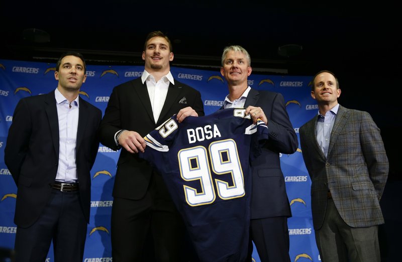 From left to right, San Diego Chargers general manager Tom Telesco, first-round draft pick Joey Bosa, head coach Mike McCoy and president of football operations John Spanos pose for photos at a news conference, Friday, April 29, 2016, in San Diego. 
